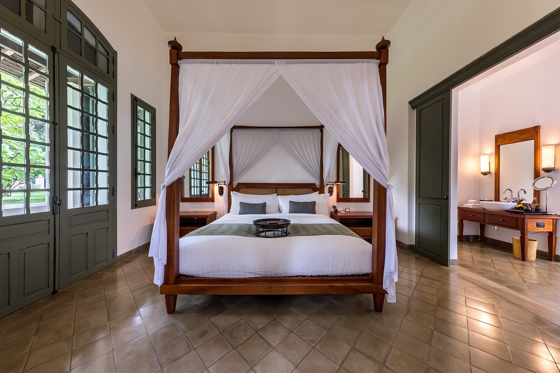 Warmly lit hotel suite bedroom with a canopy bed